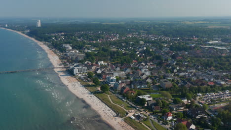 High-aerial-drone-view-of-sensational-summertime-tourist-beach-in-Scharbeutz,-Germany,-dolly-in,-sunny-windy-day